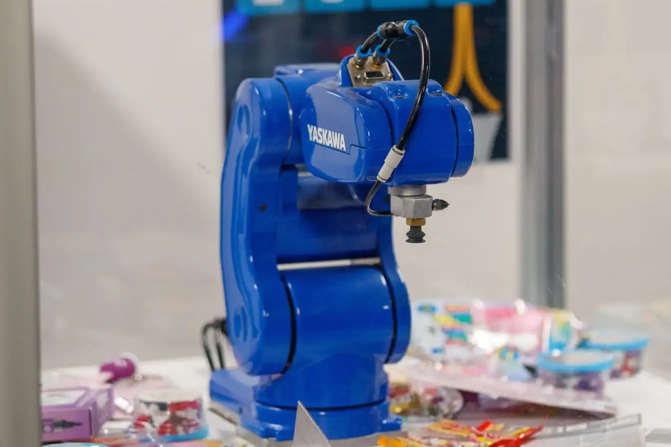 A blue industrial robot arm mounted on a stand, photographed against a plain background.
