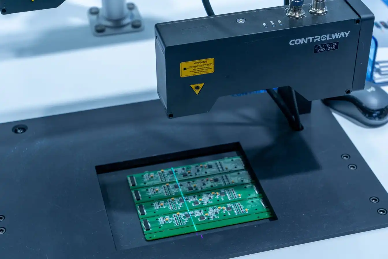 An automated optical inspection machine with a laser scanner positioned over four green printed circuit boards on a production stage.