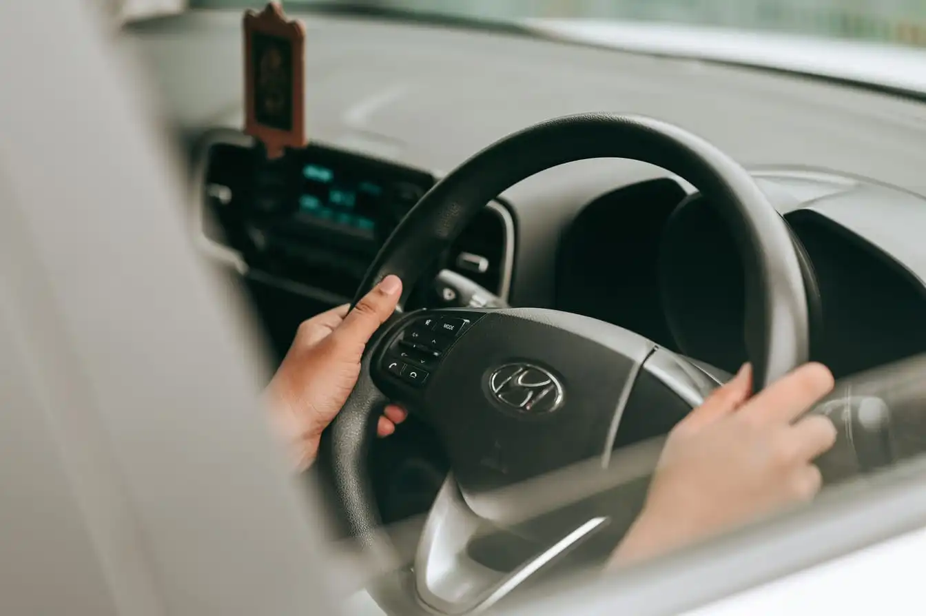 Close-up view of hands holding the steering wheel inside a car.