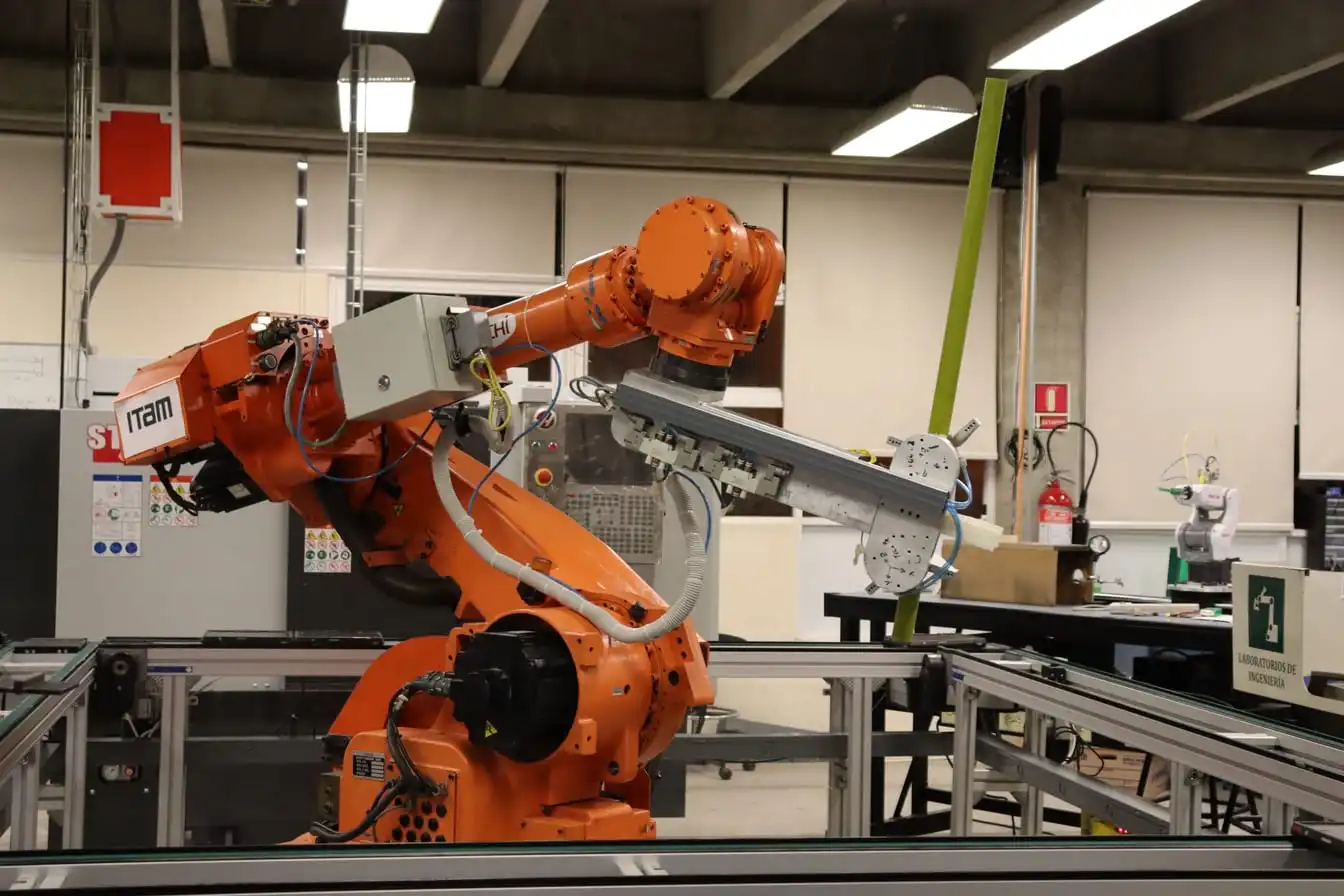 A jointed industrial robot arm standing on a workbench in a bare laboratory.