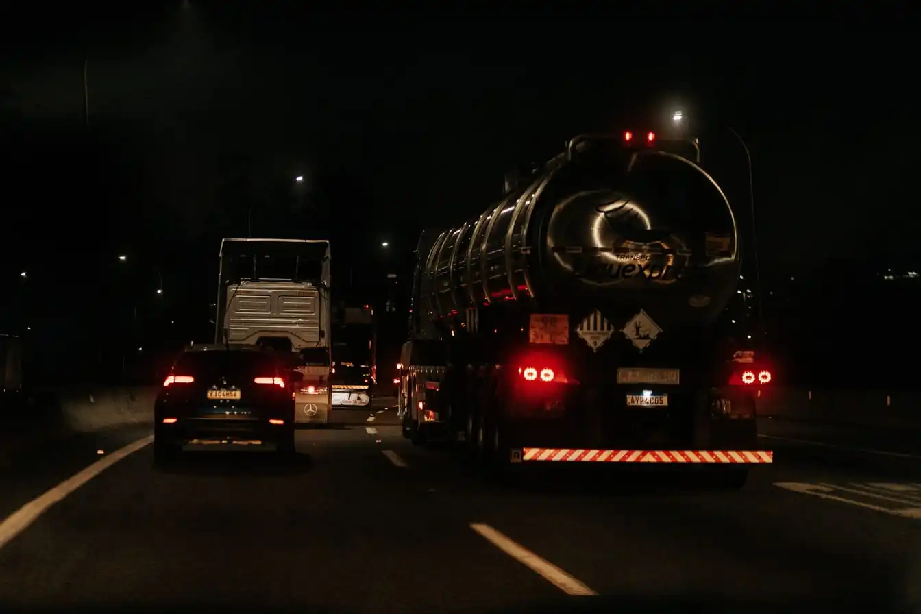 Cars and trucks on a multi-lane road after dark, headlights and tail lights visible in the traffic.