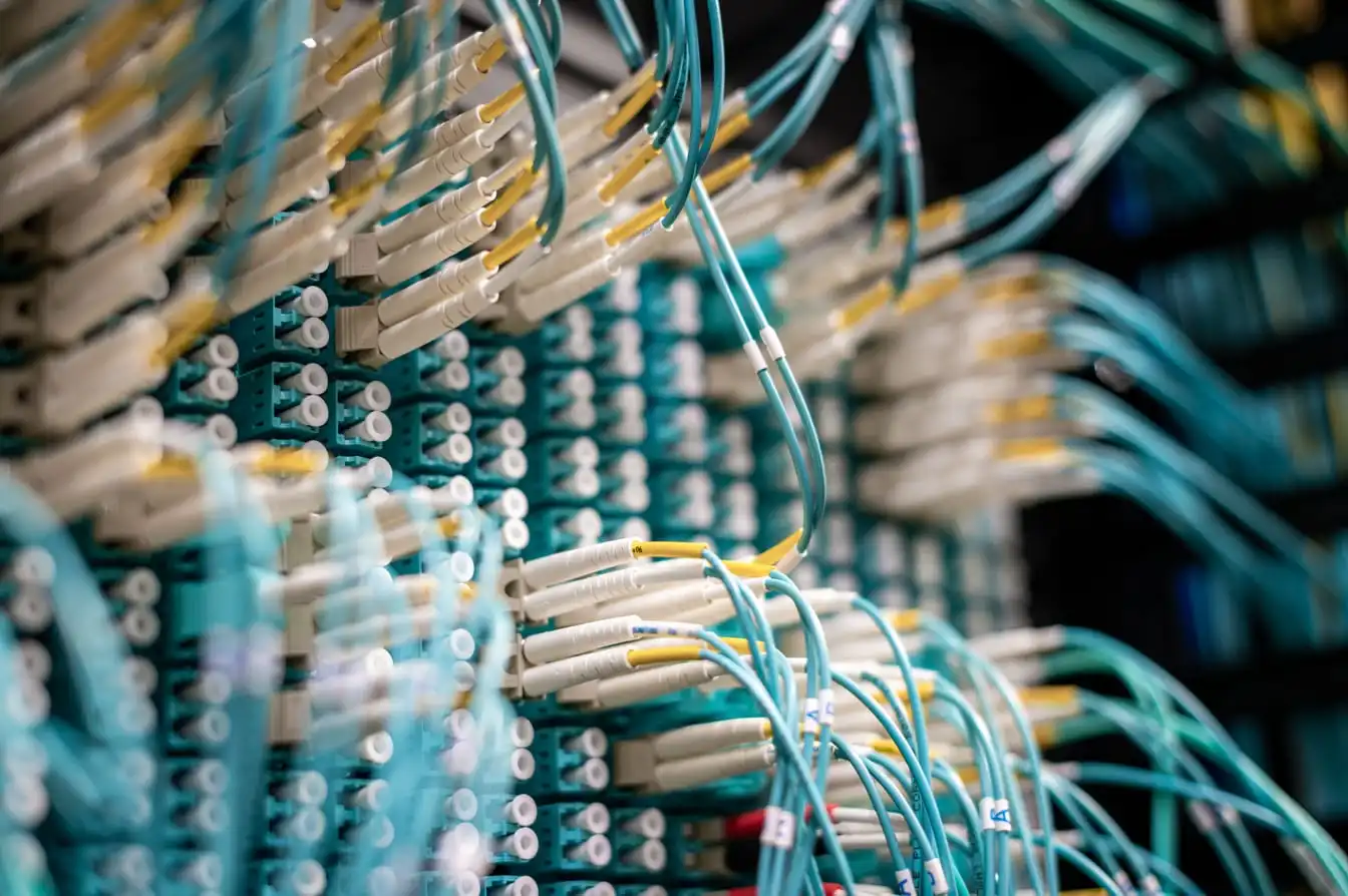 A fiber optic network switch photographed from below, with patch cables plugged into its ports.