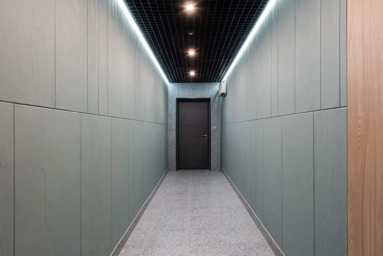 Perspective view of empty hallway with entrance door and illuminated ceiling in contemporary workplace